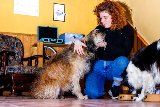 Woman kneeling, petting long-haired dog, showing bonding and care for pet