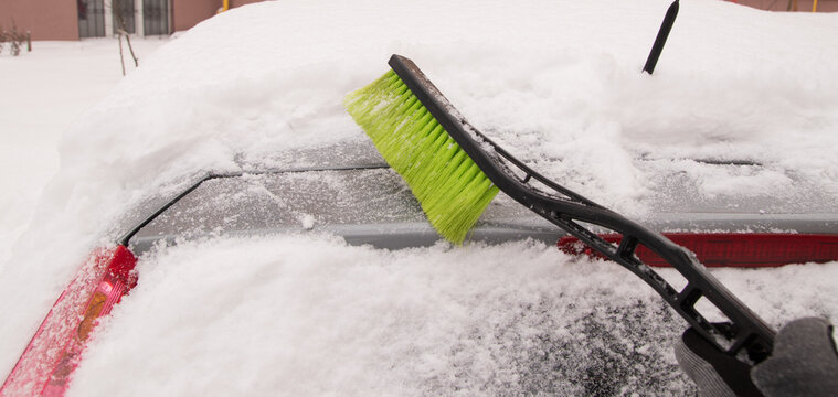 Snow removal from a car in a winter setting during morning hours