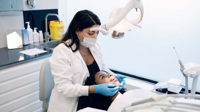Dentist in mask and gloves examining a young patient's oral health in a bright dental clinic, focusing on dental care procedure