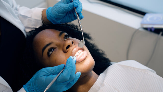 Dentist performing a routine check up on a young woman's teeth, ensuring oral health and professional care