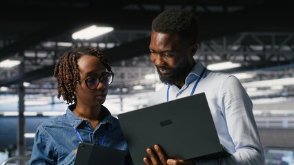 Obraz na płótnie Canvas Data center system administrators review AI and LLM visualizations on a laptop while IT specialists analyze neural network outputs and maintain stable equipment operations across the server hub.