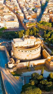 Vertical video. Rome, Italy. Castel Sant'Angelo, the cylindrical mausoleum-turned-fortress, its massive stone walls and bronze angel statue catching the first warm light of morning, Drone footage ove