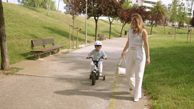 Mother teaching son to ride a bicycle in the park