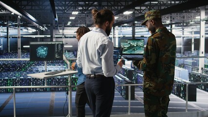 Obraz premium Military experts review a drone surveillance feed on a laptop in a data center; army units use the advanced server room for battlefield reconnaissance, intelligence software and mission operations.