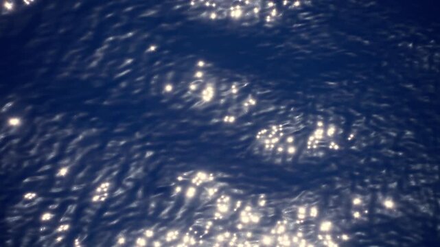 Sunlight sparkles dance across the rippled surface of deep blue ocean water. Gentle waves create mesmerizing patterns of light and shadow as bright reflections shimmer and move across the sea.