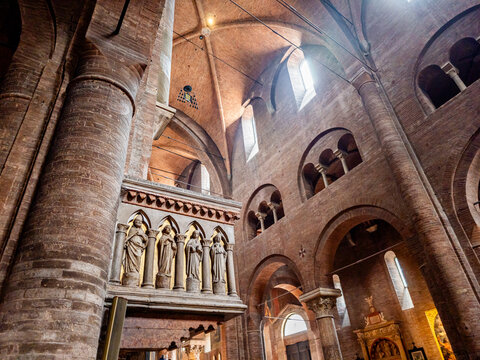 Intricate details of Modena Cathedral's Romanesque interior featuring soaring brick columns, grand arches, vaulted ceilings, and a sculpted stone pulpit with religious figures