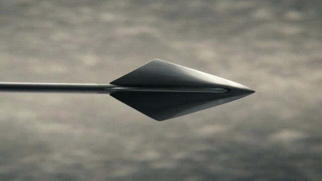 Sleek modern black metallic arrowhead flying through the air against a blurred dark textured background