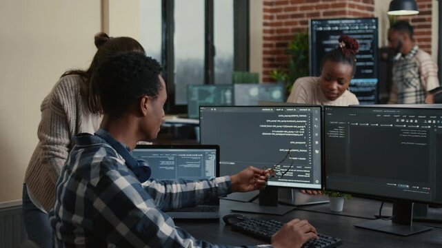 Software developer celebrates successful code compiling with a high five at a multiple monitor desk, showing teamwork, debugging success and project progress