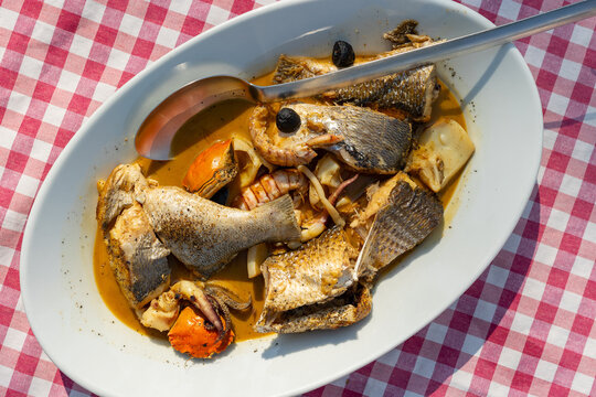 Boreto alla graisana in white oval dish on checkered tablecloth, traditional fish stew from Grado