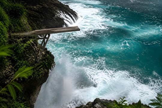 Cliff diving platform overlooking violent tropical ocean sea with fresh water spray rising from below