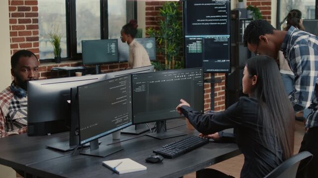 Mixed software development team brainstorms cloud computing user interface ideas beside running code screens, connecting app design, project planning and teamwork, during a data driven task.
