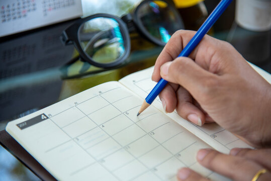 Woman hands writing empty notebook planing meeting agenda on wooden table. Female hand holding pen note Personal Organizer . Close up women hands using pen drinking coffee cup planning office paper