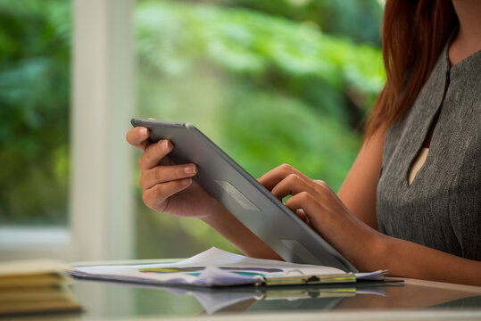Asian female people working office firm with business stuff, coffee cup. Asian Woman Hands writing planning on office paper use calendar from laptop. Woman using laptop at home online meeting,