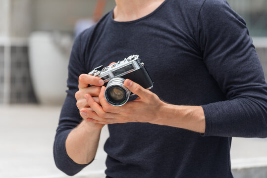 Men White People with vintage film camera take a photo. Smiling caucasian man photographer look at photo from professional camera outdoor. Young man shooting photo in green nature park outdoor travel