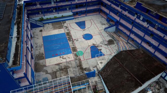 Drone aerial documentation of abandoned blue school structure with vacant pool showing deterioration and abandonment in Ciudad Madero