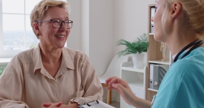 Doctor comforts senior patient in clinic consultation. Empathetic physician gives care guidance, explains options. Medical office, hand on shoulder builds trust. Kind support, trust and empathy.