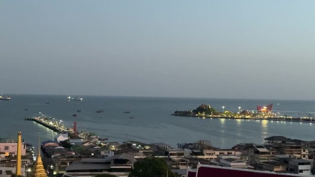 Si Racha harbor before sunrise with illuminated piers and boats in Thailand
