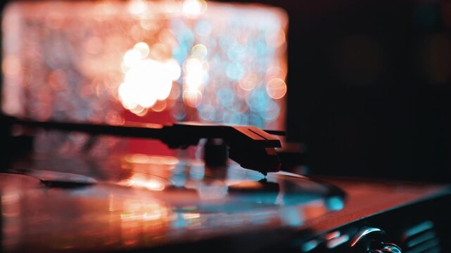 Turntable stylus playing a vinyl record. Music device with needle spinning black disc. Audio equipment for analog sound playback in moody evening light setting.