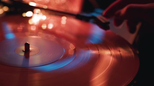Vinyl record spinning on turntable. Hand of man placing stylus on rotating disc. Analog audio playback system, vintage music technology and retro sound concept.