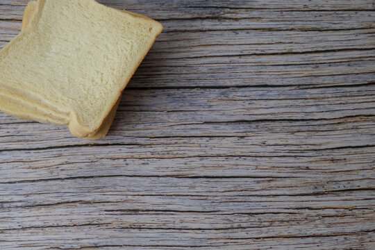 Soft white bread rest on weathered wood. Simple, rustic charm invites cozy, homemade nostalgia. Perfect for kitchens, bakery ads, or snack-themed designs. Warm tones match rustic table