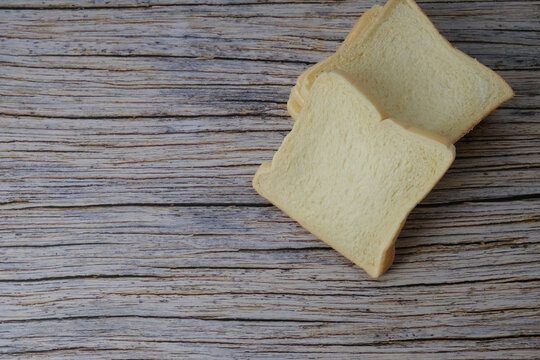 Soft white bread rest on weathered wood. Simple, rustic charm invites cozy, homemade nostalgia. Perfect for kitchens, bakery ads, or snack-themed designs. Warm tones match rustic table
