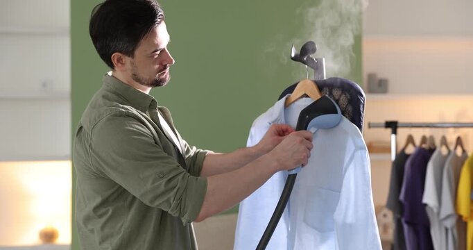 Man steaming shirt with modern steamer at home