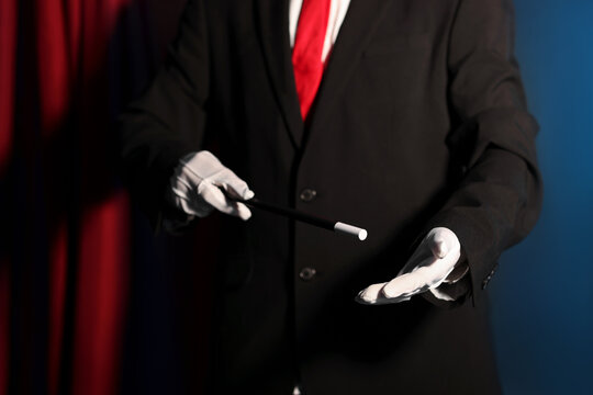 Magician showing trick with wand on stage, closeup