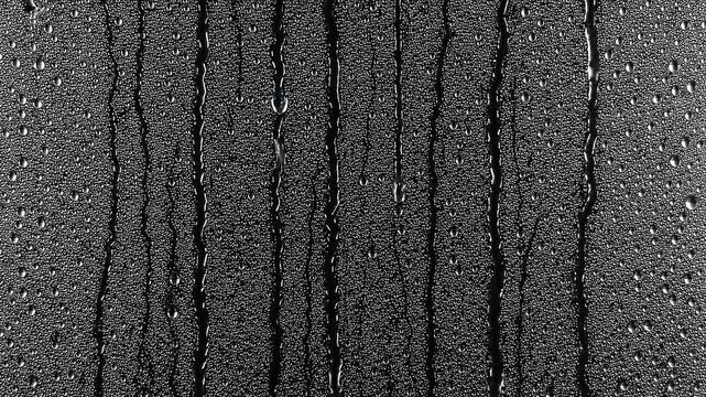 Black and white water droplets dripping down a glass surface as a cinematic overlay video for blending.