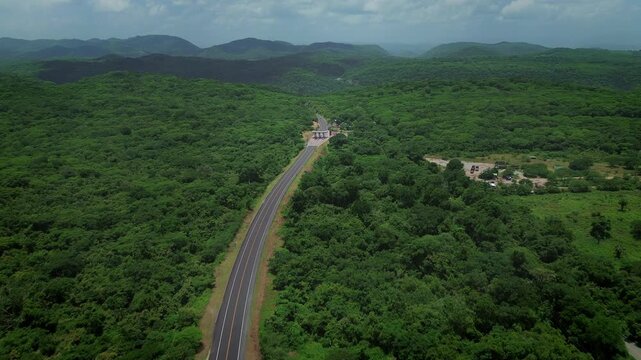 Drone forward approach of Rio Verde Ciudad Valles highway showing toll booth and dense tropical mountain forest landscape