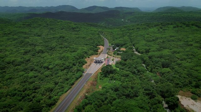 Drone forward approach of Rio Verde Ciudad Valles highway showing toll booth and dense tropical mountain forest landscape