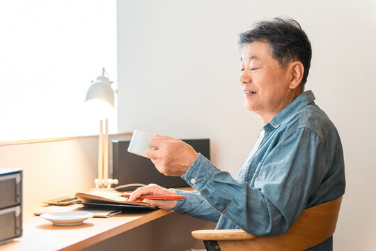 A senior man sitting in his home's study space (study corner, custom-built house)
