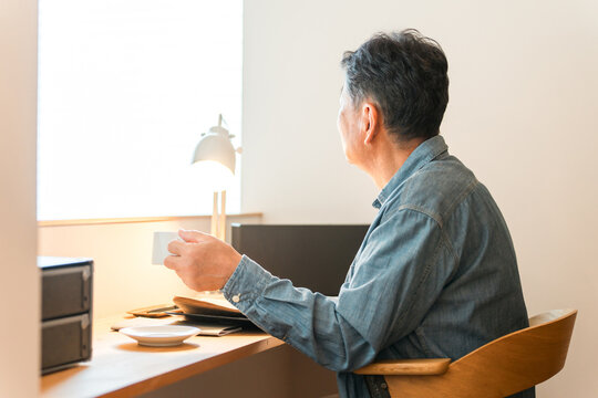A senior man sitting in his home's study space (study corner, custom-built house)