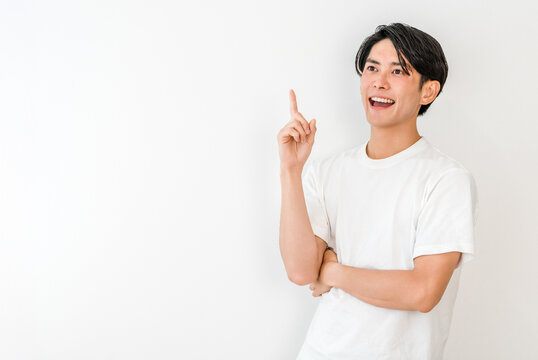 A young Asian man in a T-shirt pointing (point, introduction, guidance, recommendation, direction)
