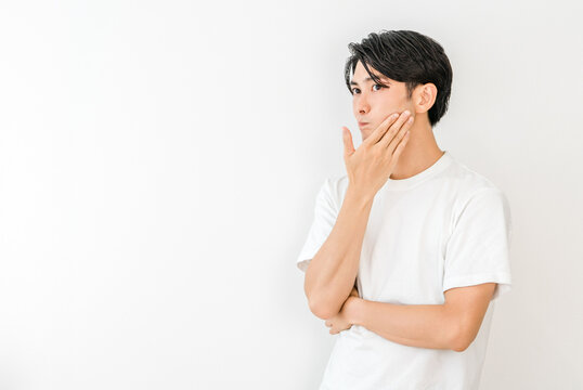 A young Asian man resting his chin on his hand (worrying, troubled, distressed, anxious, imagining)