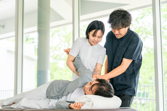 マッサージ,理学療法の研修を受ける若い女性スタッフと教える理学療法士の男性