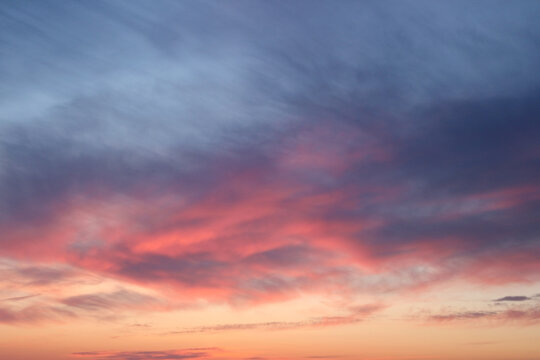 A delicate dawn sky with floating clouds in pink, orange, and purple tones