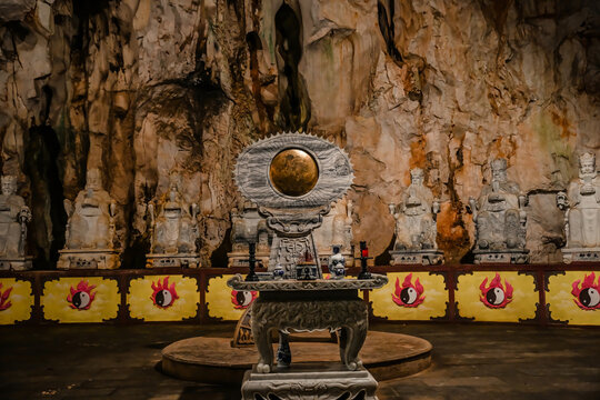 DA NANG, VIETNAM - APRIL 15, 2026:Detailed view of a stone underground altar with a traditional bronze mirror disc inside the mystical Am Phu cave of Marble Mountains in Da Nang Vietnam
