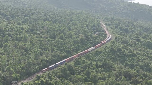 Freight and passenger trains travel through the breathtaking Hai Van Pass in Hue, Vietnam, winding along dramatic coastal mountains. Scenic railway transportation with tunnels, lush forests, and panor