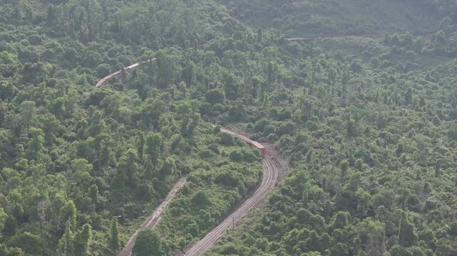 Freight and passenger trains travel through the breathtaking Hai Van Pass in Hue, Vietnam, winding along dramatic coastal mountains. Scenic railway transportation with tunnels, lush forests, and panor