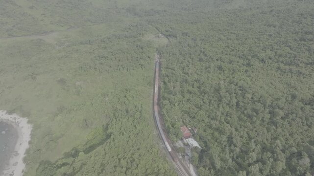 Freight and passenger trains travel through the breathtaking Hai Van Pass in Hue, Vietnam, winding along dramatic coastal mountains. Scenic railway transportation with tunnels, lush forests, and panor