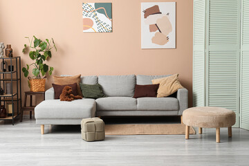Modern living room interior with gray sectional sofa, decorative pillows, Abstract art, and a small brown dog © Pixel-Shot