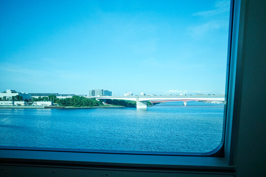 Scenic view of a bridge over a blue river and cityscape seen through a train window during travel