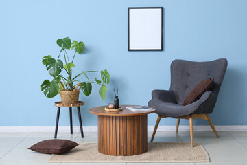 Fototapeta premium Comfortable armchair, houseplant and coffee table in interior of living room
