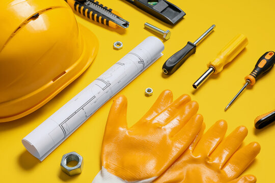 Composition with different construction tools, house plant and hardhat on yellow background