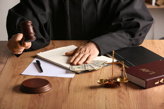 Male judge with gavel, documents and money at table in office
