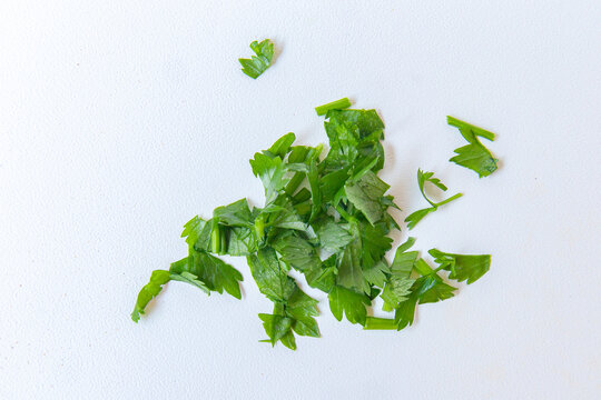 chopped fresh parsley herb isolated on white. Sliced cilantro leaves, raw garden parsley, chervil, coriander pieces on white background top view
