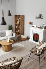 Obraz premium Interior of modern living room with fireplace, grey sofa and chairs