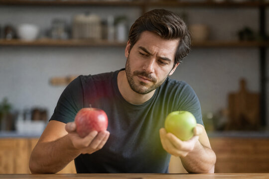 Man Comparing Red and Green Apples Indoors