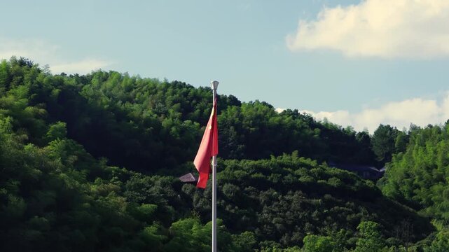Chinese flag blown by the small breeze with mountains in the background