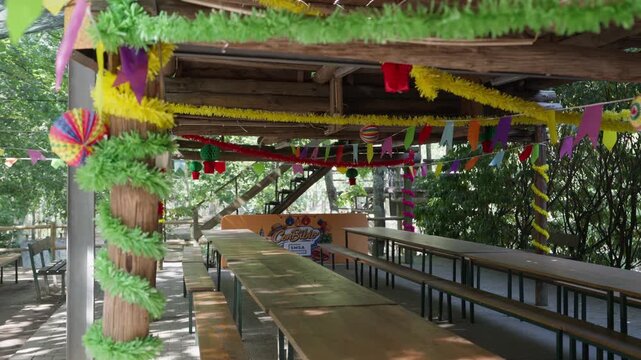 Long wooden tables under colorful bunting and streamers at outdoor venue